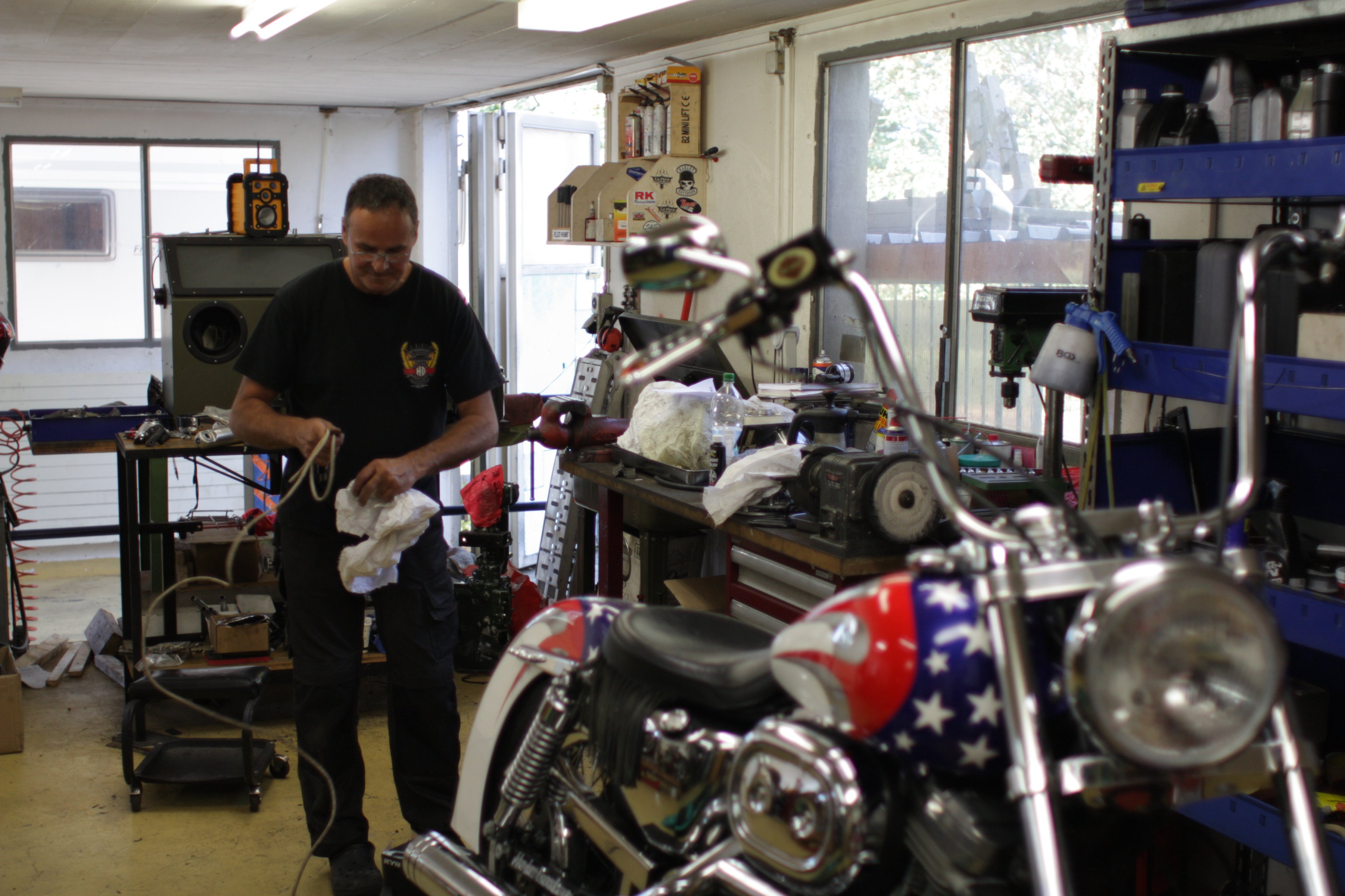 Christian travaille sur une moto custom au réservoir étoilé